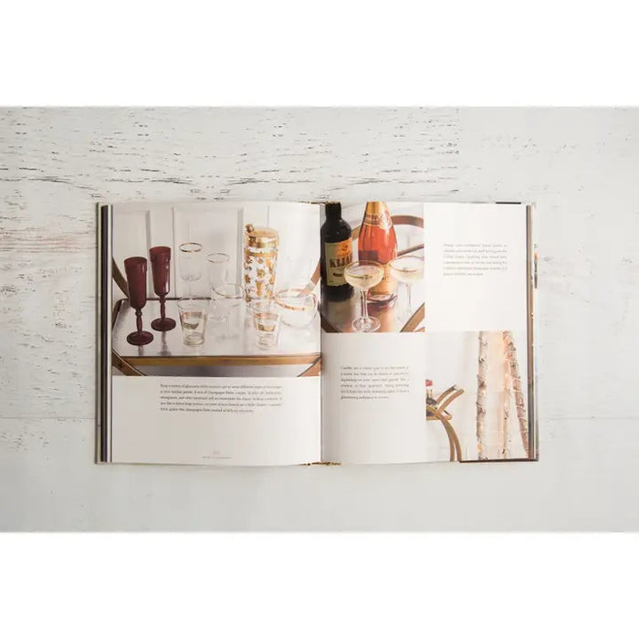 A close-up of THE ART OF THE BAR CART BY VANESSA DINA from CHRONICLE BOOKS, featuring a gold-patterned spine and an illustrated bar cart on the cover—ideal for drink ideas and elegant home bar decor.