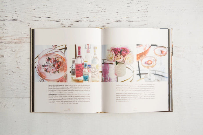 A close-up of THE ART OF THE BAR CART BY VANESSA DINA from CHRONICLE BOOKS, featuring a gold-patterned spine and an illustrated bar cart on the cover—ideal for drink ideas and elegant home bar decor.