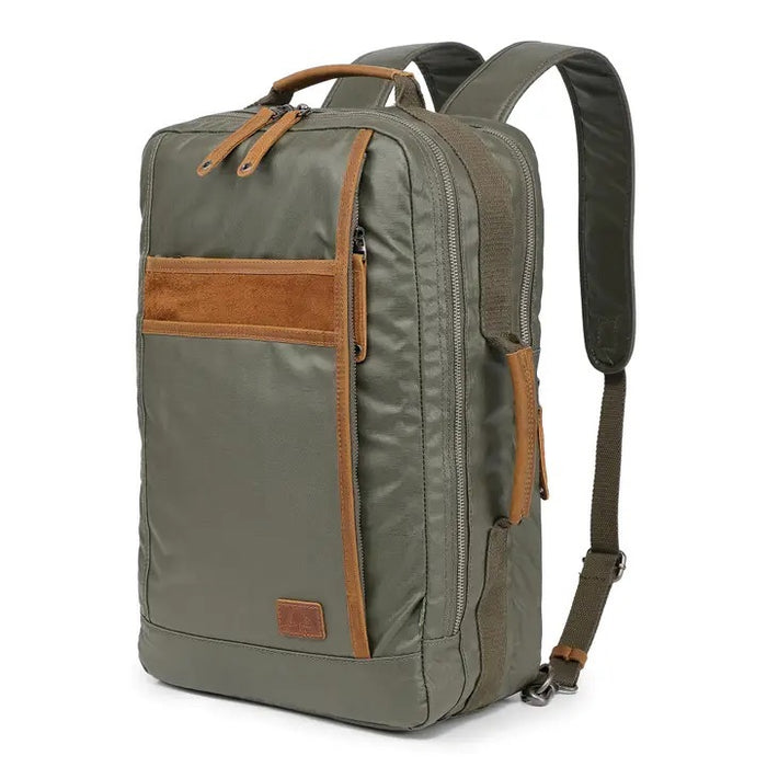 The TSD BRAND Madrone Coated Canvas Backpack in army green features brown leather accents, zippers, a top flap, side handles, metal rings, and a leather logo patch; shown lying flat to display these details.