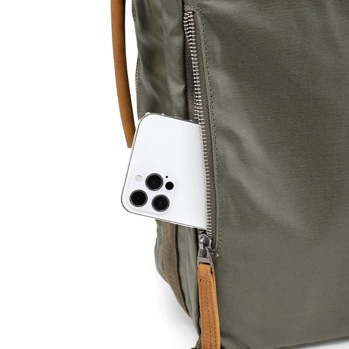 The TSD BRAND Madrone Coated Canvas Backpack in army green features brown leather accents, zippers, a top flap, side handles, metal rings, and a leather logo patch; shown lying flat to display these details.