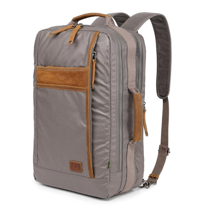 A close-up of the TSD BRAND - MADRONE Coated Canvas Backpack in Grey shows its brown leather accents and an unzipped front pocket with a black wallet partially visible inside.