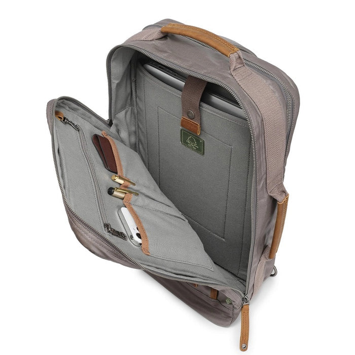 A close-up of the TSD BRAND - MADRONE Coated Canvas Backpack in Grey shows its brown leather accents and an unzipped front pocket with a black wallet partially visible inside.