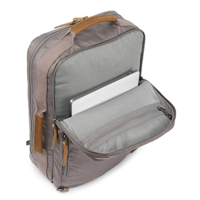 A close-up of the TSD BRAND - MADRONE Coated Canvas Backpack in Grey shows its brown leather accents and an unzipped front pocket with a black wallet partially visible inside.