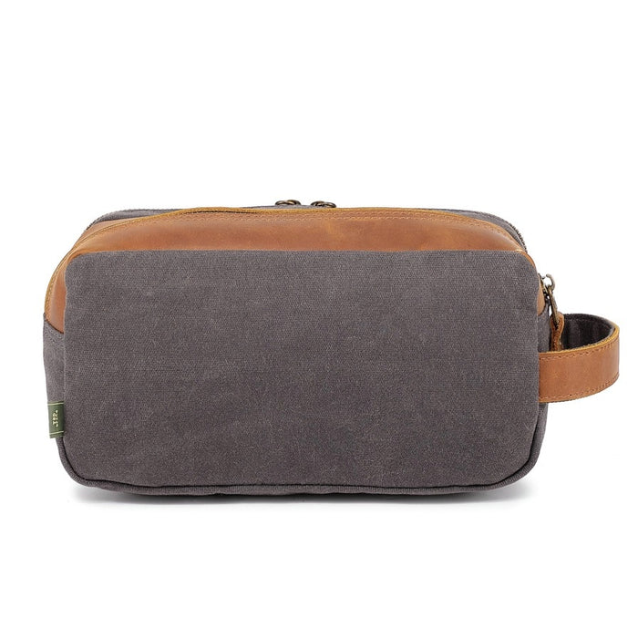 The TSD BRAND - Turtle Ridge Toiletry Bag in grey features waxed canvas, leather details, and a zip closure. It is open to show neatly organized travel essentials inside—bottles, a tube, a brush, and a white rectangular item.