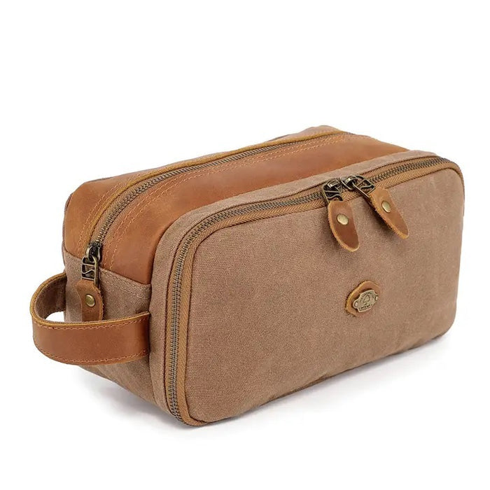 The TSD BRAND Turtle Ridge Toiletry Bag in khaki features leather accents, two zippered compartments, a side handle, and a small logo patch on the front pocket.