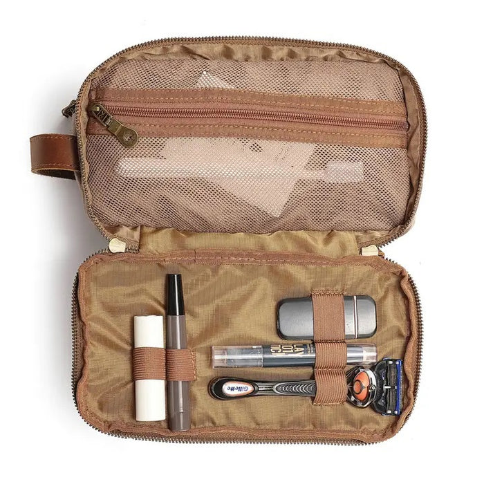 The TSD BRAND Turtle Ridge Toiletry Bag in khaki features leather accents, two zippered compartments, a side handle, and a small logo patch on the front pocket.