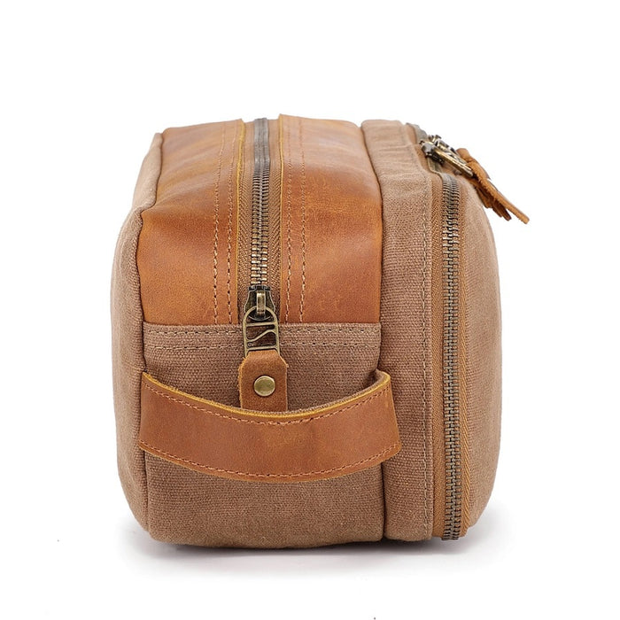 The TSD BRAND Turtle Ridge Toiletry Bag in khaki features leather accents, two zippered compartments, a side handle, and a small logo patch on the front pocket.