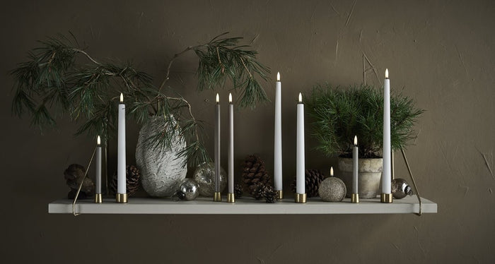 Two PIFFANY UYUNI Ivory Slim Taper Candles (1x12.6) with small yellow flames stand upright side by side against a plain white background, exuding timeless elegance.