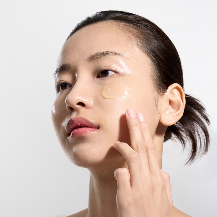 Woman applying cream to her face with a white background