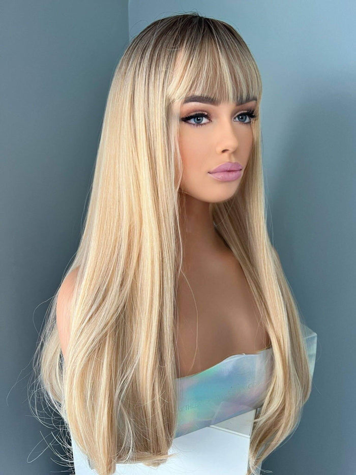 Blonde wig with bangs on a mannequin head against a gray background