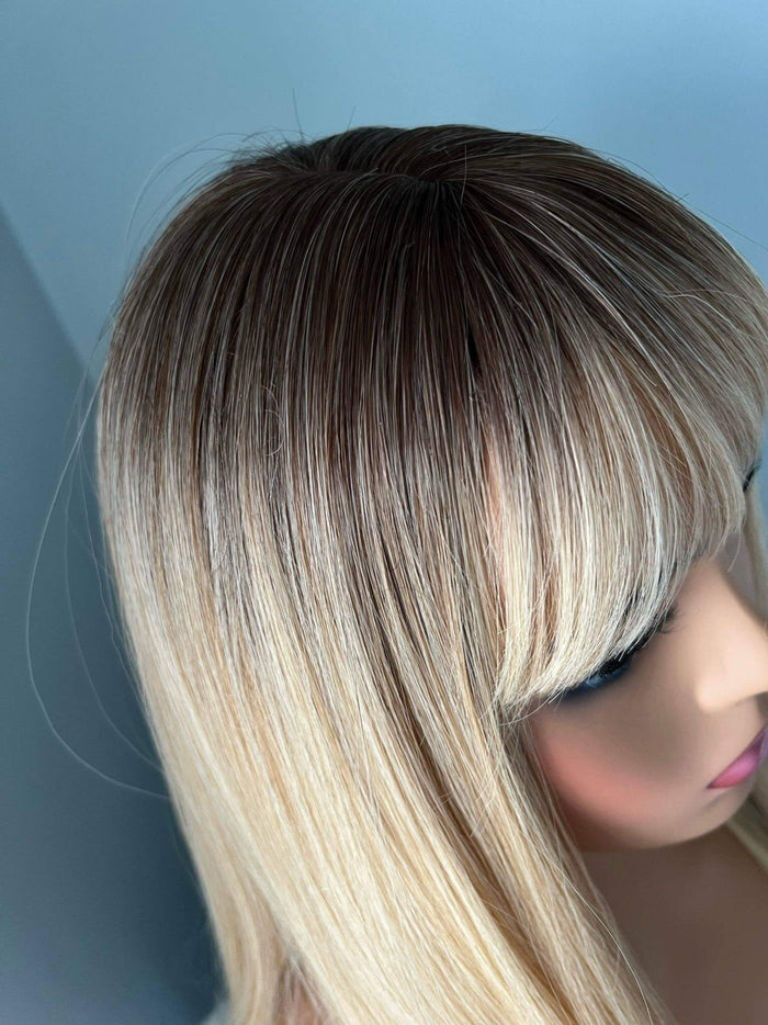 Mannequin head with a wig featuring a gradient from dark brown to blonde on a blue background