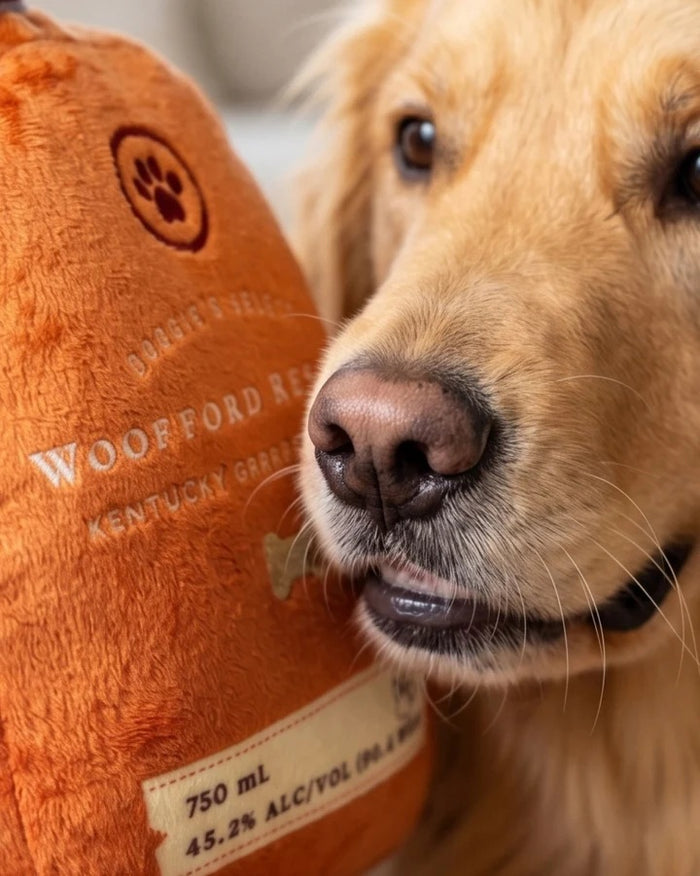 Introducing the WOOFFORD RESERVE BOURBON DOG TOY by HAUTE DIGGITY DOG—this plush dog toy is cleverly designed to resemble a whiskey bottle, complete with whimsical dog-themed text and a paw print on the label. Perfect for pups who enjoy playful style and cuddly fun!.