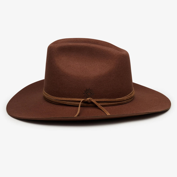 The WYETH Costa Cowboy Hat in Cinnamon features a wide brim, pinched crown, and thin suede trim tied in a bow. This adjustable hat by WYETH is shown on a white background.