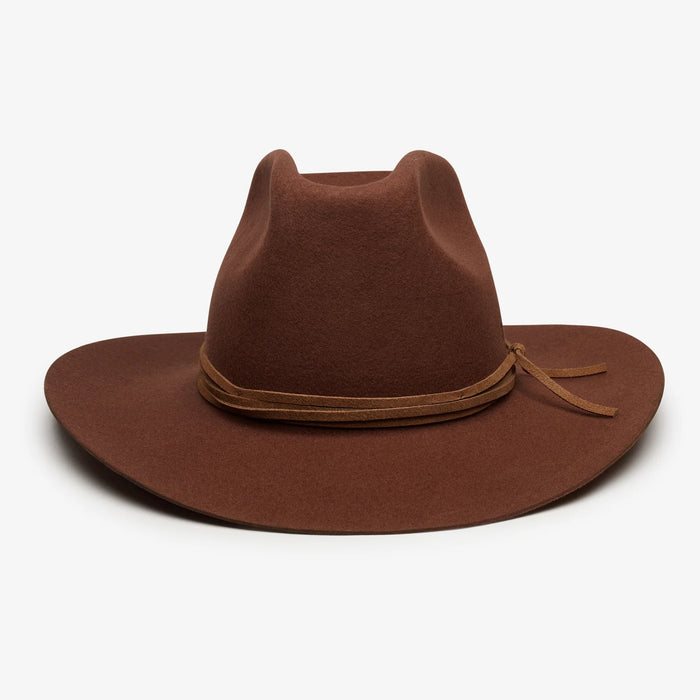 The WYETH Costa Cowboy Hat in Cinnamon features a wide brim, pinched crown, and thin suede trim tied in a bow. This adjustable hat by WYETH is shown on a white background.
