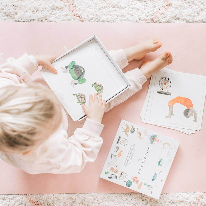 Child engaging with Yoga Flash Cards on a pink yoga mat, promoting mindfulness and movement.