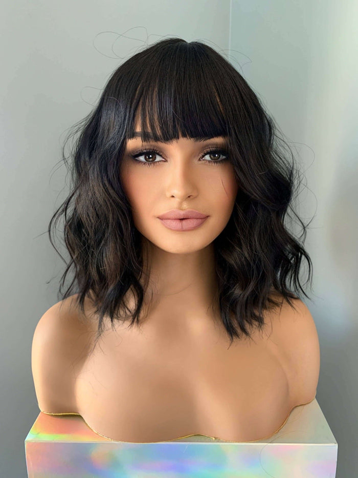 Woman with styled black hair against a neutral background