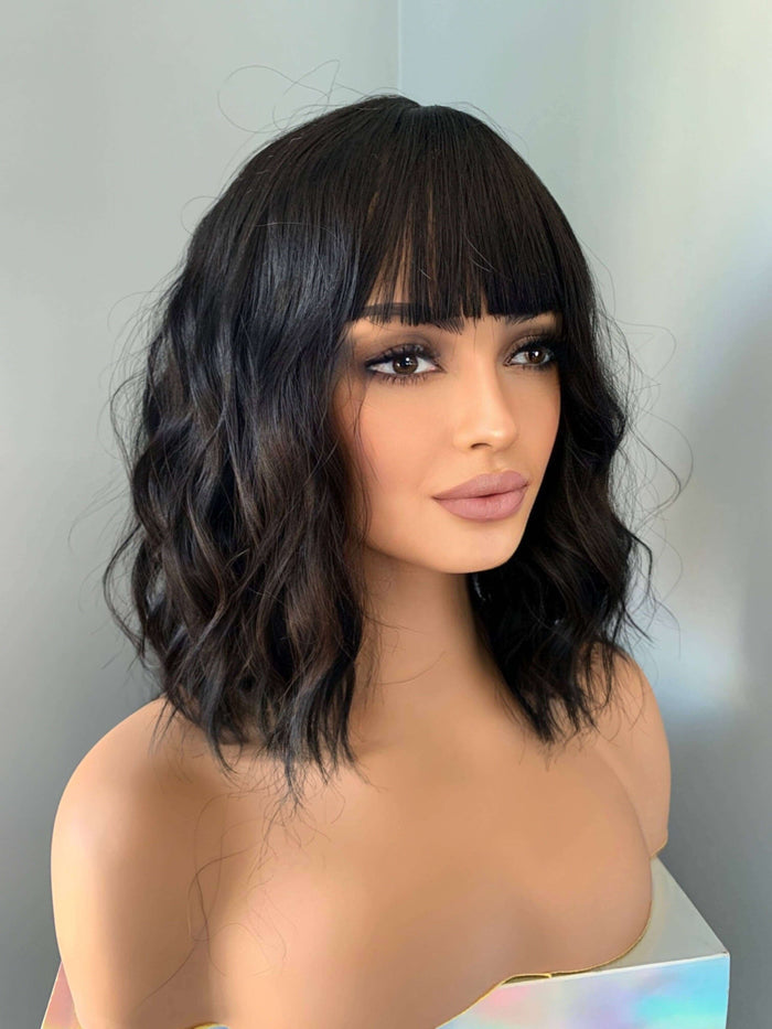 Woman with styled black hair and makeup against a neutral background