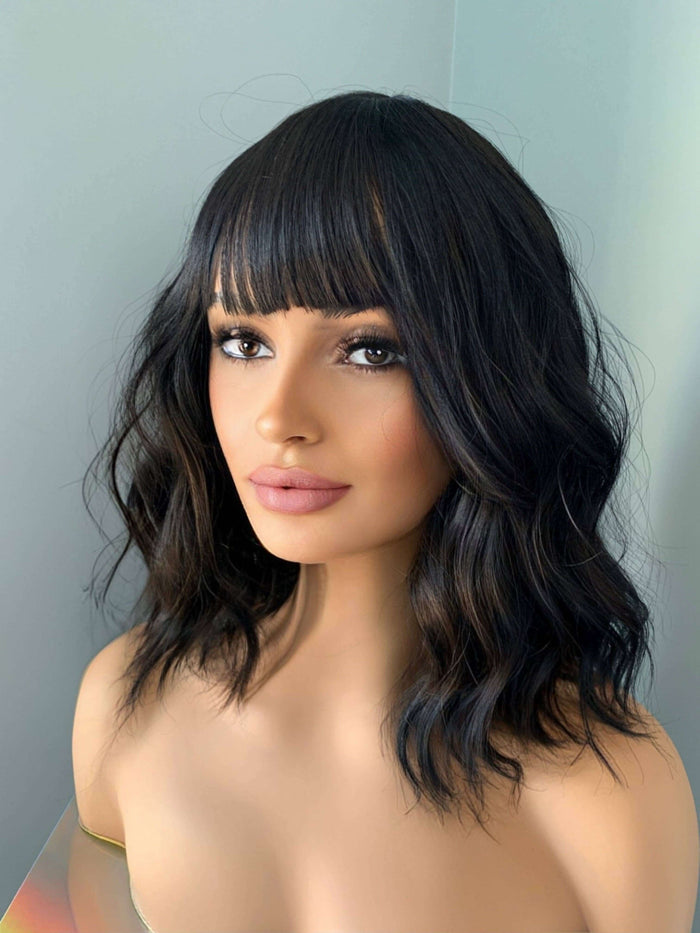 Mannequin head with black wavy hair and bangs against a light gray background